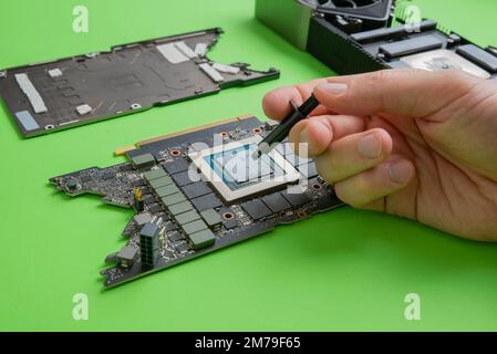 Changing the thermal paste on the graphics processor. Disassembled graphics card on the table. Old graphics card service Stock Photo