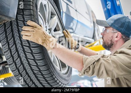Professional Mechanic Preparing to Remove the Rear Wheel From the Car During the Seasonal Tire Change. Automobile Service Theme. Stock Photo