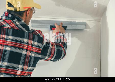 Professional Construction Worker Applying Plaster on Walls Using Plastering Spatula Tool. Interior Renovation Work. Stock Photo
