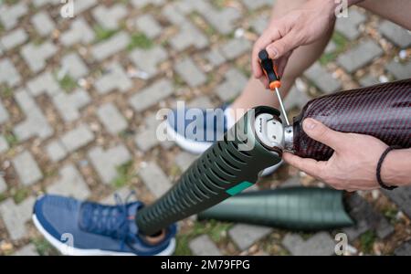 A man adjusts the bolts of his artificial leg before running Stock Photo