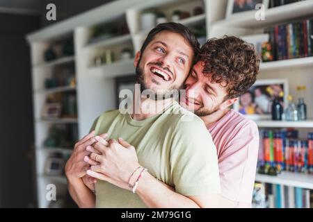 Attractive couple of gay men hugging and embracing each other at home. Stock Photo