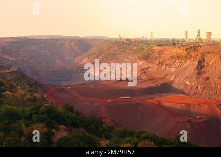 Bulldozers and trucks in quarry with red ground. Mining iron ore in Kriviy Rih, Ukraine. Industrial landscape Stock Photo