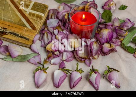 Dried roses, candle and book on a cloth Stock Photo