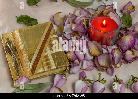 Dried roses, candle and book on a cloth Stock Photo