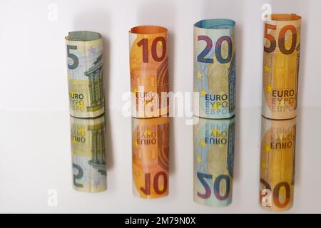 Rolled euro banknotes reflected in a mirror with copy space Stock Photo