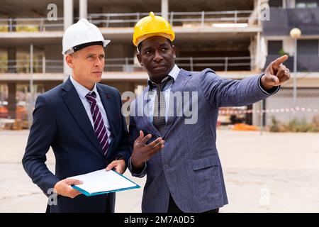 Architects talking about project documentation on construction plant Stock Photo