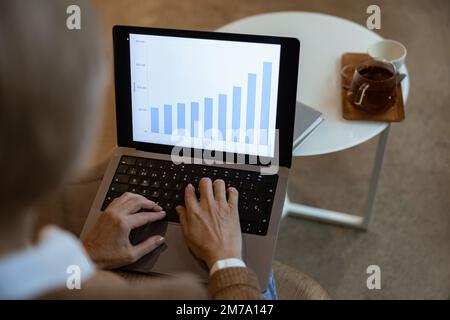 Close up of middle aged businesswoman using laptop works with statistical data in cozy cafe Stock Photo