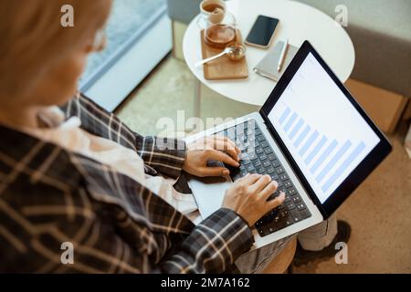 Close up of middle aged businesswoman using laptop works with statistical data in cozy cafe Stock Photo