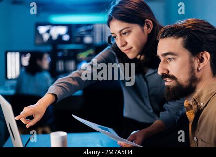 Two business stock trader colleagues working in dark office Stock Photo