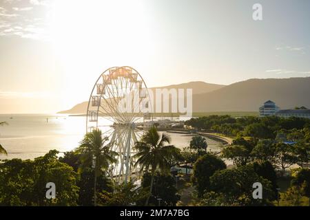 Golden hour over the ferris wheel, treetops, lagoon and hilly backdrop of Cairns Esplanade - Coral Sea, Cairns; Far North Queensland, Australia Stock Photo