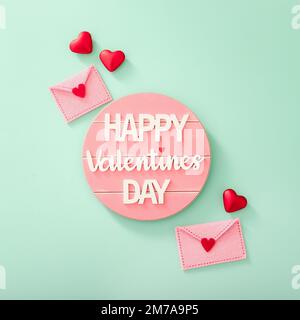 Happy Valentine's Day message, red hearts and felt envelopes on color background, top view Stock Photo
