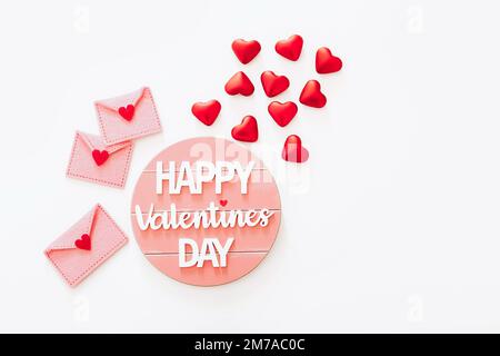 Wooden Happy Valentine's Day message with felt envelopes and red hearts on white background Stock Photo