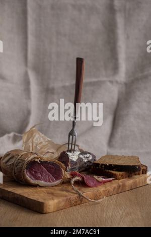 Close-up piece of jamon on fork, light appetizer, homemade food, selective focus Stock Photo