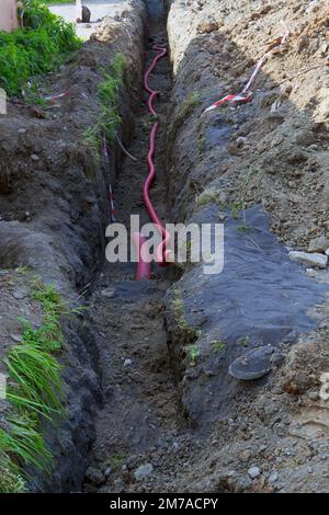 Laying electrical cables in a trench at a construction site close-up. Laying underground electric cable for new developments. Stock Photo