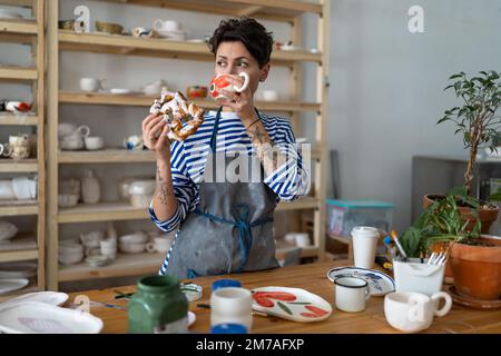 Italian young female owner in pottery workshop has coffee break, successful small business concept Stock Photo