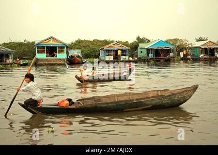 Children travelling by boats in a background of houseboats of a floating village on Tonle Sap, the largest freshwater lake in Cambodia, on this 2013 photo. Since at least November 2021, Cambodian authorities have been trying to protect the area's natural resources—including fish sanctuaries—more tightly, the Phnom Penh Post reported on Jan 3, 2023.   Fisheries crimes in the area will be suppressed again in 2023, following successful campaigns leading to an increase in fisheries production last year. Stock Photo