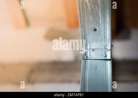 Close-up of a metal profile frame for a wall. Room divider under construction. Connection using self-tapping screws with a drill. Stiffening ribs in a Stock Photo