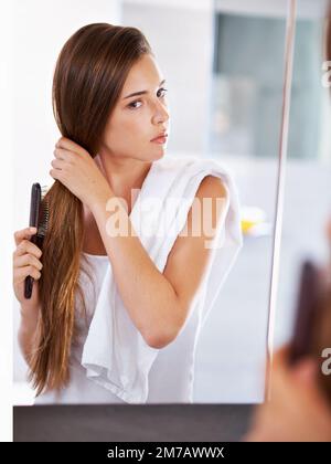 Getting that sleek and shiny look. an attractive young woman using a flat iron. Stock Photo