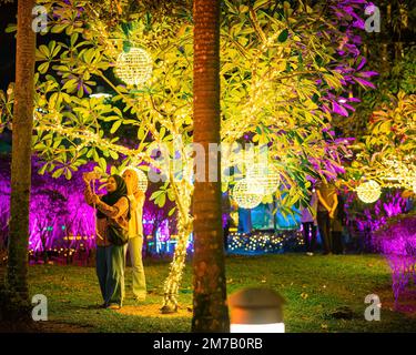 Putrajaya, Malaysia - July 18, 2022 Poeple taking photos with Led lights on the trees in the garden. Neon fairy party. Stock Photo