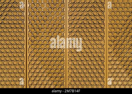 Detail of yellow ochre metal plates with hexagonal pattern covering building wall - bright background in sunlight Stock Photo