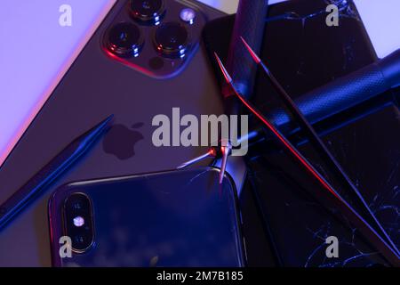 South Tyrol, Italy - Jan. 7. 2023: Smartphone repair tools, tweezers, screwdriver on top of Apple iPhone 13 Pro Stock Photo