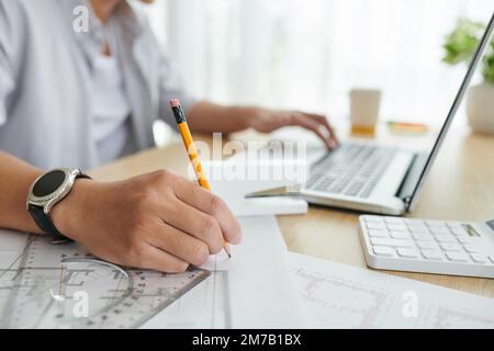 Closeup image of architect making correction in construction plan on office table Stock Photo