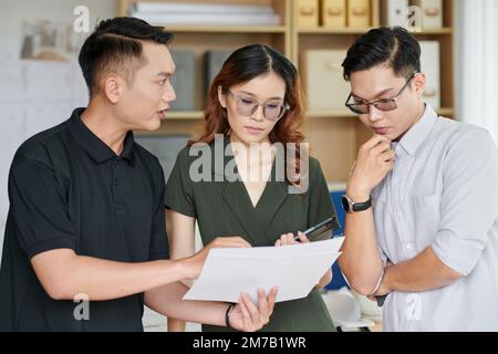 Group of young architects discussing apartment blueprint Stock Photo