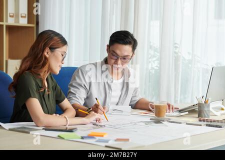 Team of young architects checking blueprint and discussing project of interior design Stock Photo