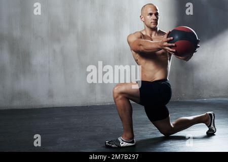 Working those muscles. a man working out with a medicine ball at the gym. Stock Photo