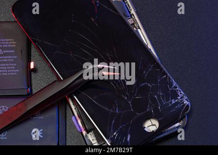 South Tyrol, Italy - Jan. 7. 2023: Tweezers on top of broken Apple iPhone display. Repairing broken Smartphone Stock Photo