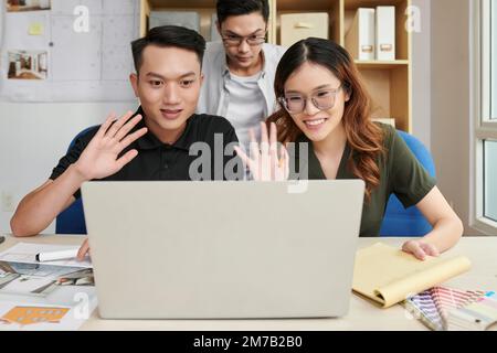 Team of young architects and interior designers video calling client Stock Photo