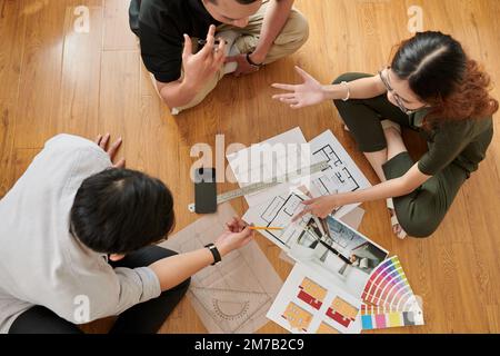 Team of young interior designers discussing new project when sitting on floor in architecture bureau, view from above Stock Photo
