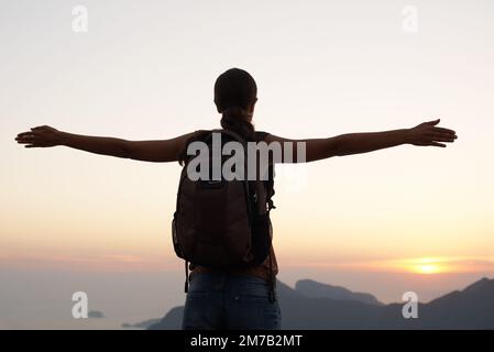 Feeling a part of something beautiful. Silhouette shot of a young woman standing against the sky. Stock Photo