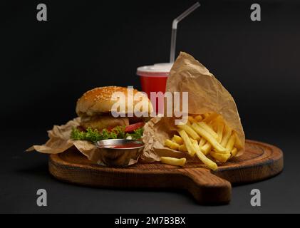 Homemade delicious double burger with beef, lettuce, bacon, tomato and cheese on a wooden background. Stock Photo