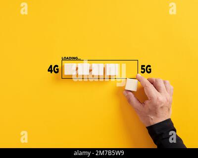 Transformation of wireless network connection technology from 4G to 5G. Hand places a wooden cube to the loading bar with the words 4G and 5G. Stock Photo