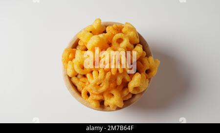 Cheetos is a crunchy corn puff snack. Bright orange cheese puffs in a wooden bowl. Stock Photo