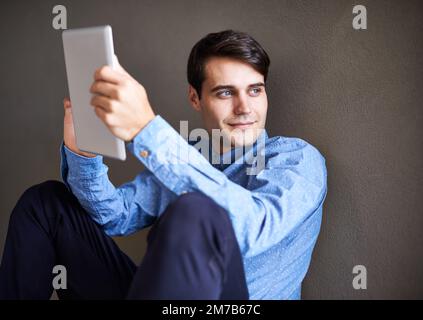 He has dreams to be the next Steve Jobs. A young businessman looking thoughtful while sitting with his digital tablet. Stock Photo