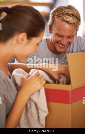 Uncovering treasures while packing. a young couple unpacking boxes on moving day. Stock Photo