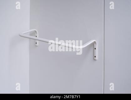 White modern clothes drying rack, curved shape on the white wall background at the terrace in hotel room. Empty white wall mounted laundry towel dryin Stock Photo