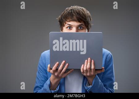 young man hiding his face with laptop Stock Photo