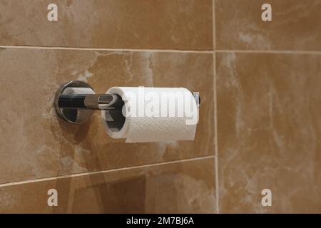 Roll of toilet paper on wall mounted holder, selective focus Stock Photo