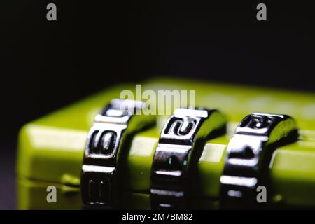 A macro shot of a green padlock with a combination unlocking mechanism on dark background Stock Photo