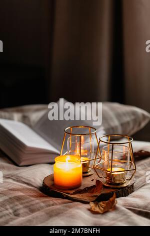 warm cozy bedroom winter or autumn concept, candles on tray and a book Stock Photo