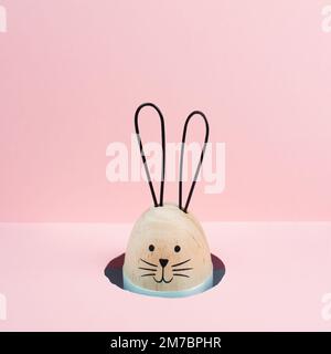 Easter bunny or rabbit peeking out a hole, spring holiday greeting card, pink pastel color, minimailism Stock Photo