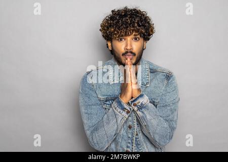 Mindful happy bearded indian business man praying in meditation holding hands in namaste, feeling mental balance, stress free, meditating in prayer, d Stock Photo