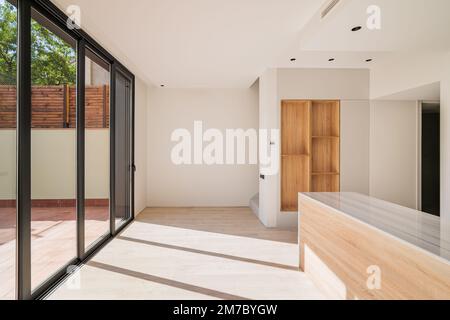 Large bright spacious kitchen with wooden furniture and closed black metal sliding glass doors with access to the terrasse. Modern design of the Stock Photo