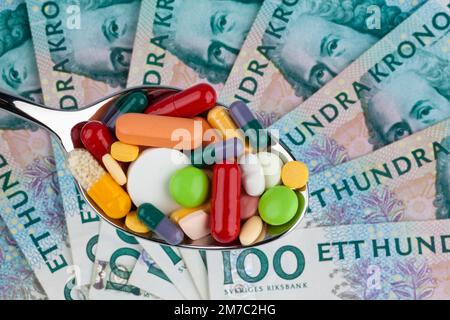 colourful pills on a spoon against Swedish krona, cutout Stock Photo
