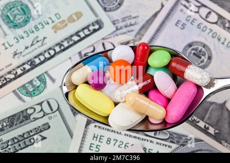 colourful pills on a spoon against Dollar bills, cutout Stock Photo