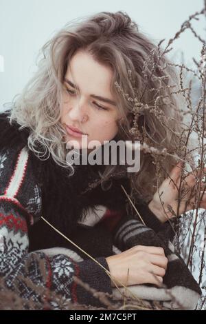 Close up thoughtful woman in sweater on winter meadow portrait picture Stock Photo