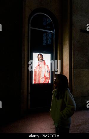 Stone Island window of flagship store in Milano, Italy. An image with coloured man wearing a jacket. How colored african models are used in fashion Stock Photo